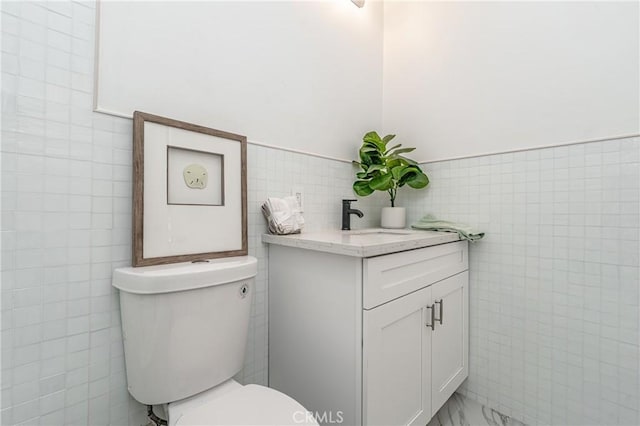 bathroom with vanity, toilet, and tile walls