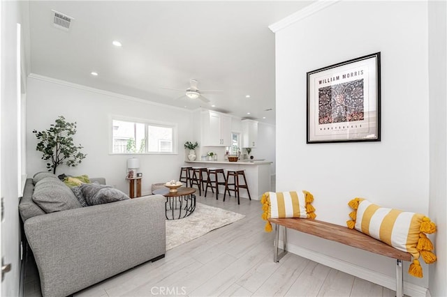 living room with ceiling fan, light wood-type flooring, and ornamental molding