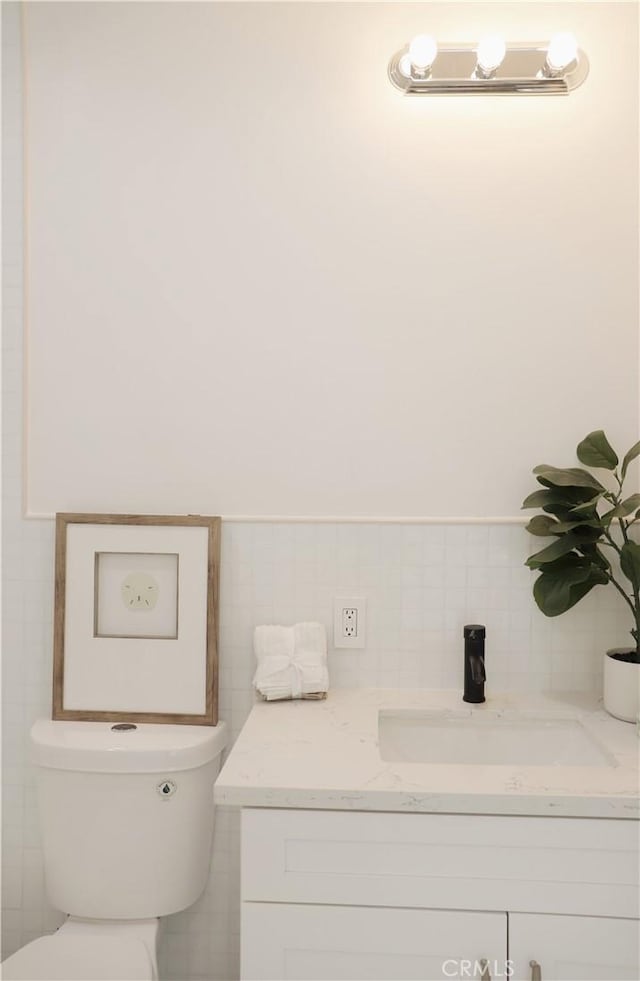 bathroom featuring vanity, tile walls, and toilet