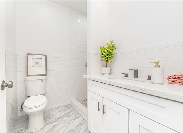 bathroom featuring vanity, toilet, and tile walls