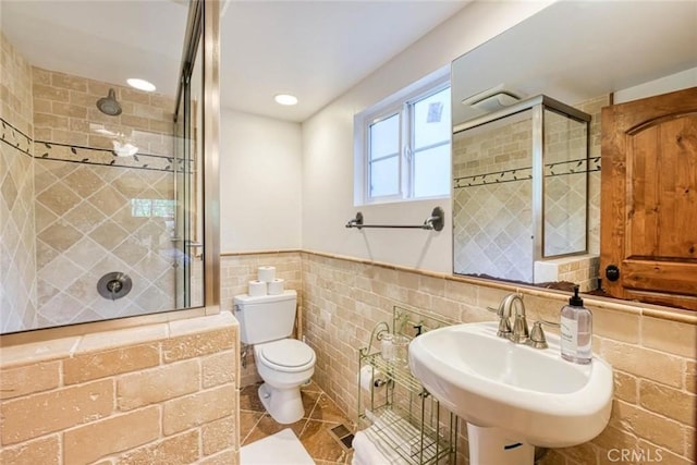 bathroom with tiled shower, toilet, tile walls, and sink