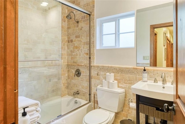 full bathroom featuring vanity, toilet, tile walls, and enclosed tub / shower combo