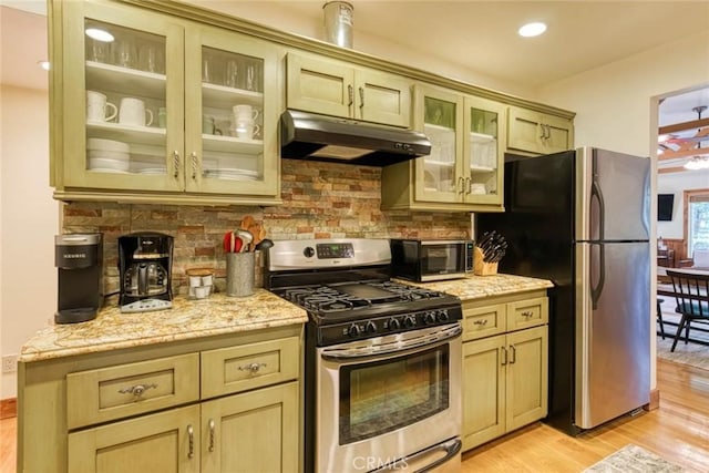 kitchen featuring appliances with stainless steel finishes, tasteful backsplash, light stone counters, cream cabinets, and light hardwood / wood-style floors