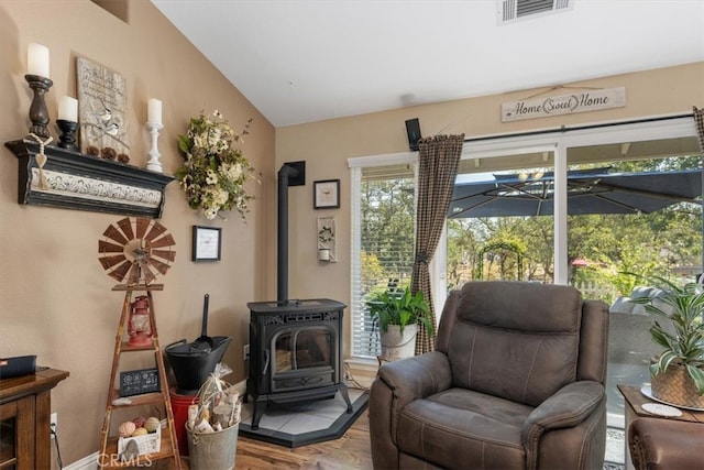 sitting room featuring wood-type flooring, vaulted ceiling, and a wood stove