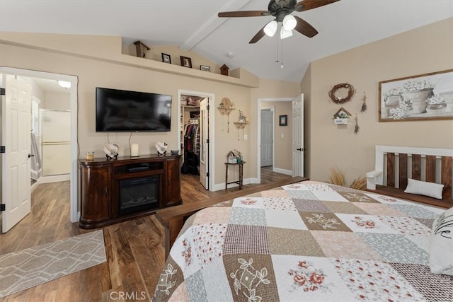 bedroom featuring lofted ceiling with beams, a spacious closet, a closet, wood-type flooring, and ceiling fan