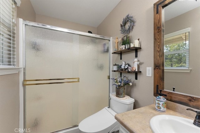 bathroom featuring a shower with door, vanity, and toilet