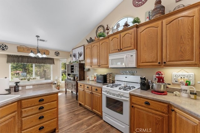 kitchen featuring hanging light fixtures, vaulted ceiling, white appliances, dark hardwood / wood-style flooring, and a chandelier