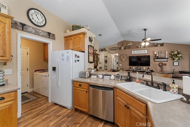 kitchen featuring ceiling fan, lofted ceiling, stainless steel dishwasher, white fridge with ice dispenser, and washer and dryer