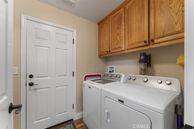 laundry area featuring a textured ceiling, washer and clothes dryer, hardwood / wood-style floors, and cabinets