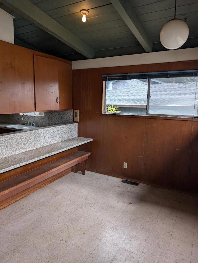 interior space with sink, beam ceiling, wooden walls, and wooden ceiling