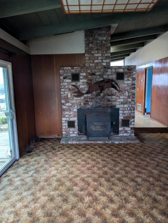 unfurnished living room featuring carpet, beamed ceiling, and wood walls