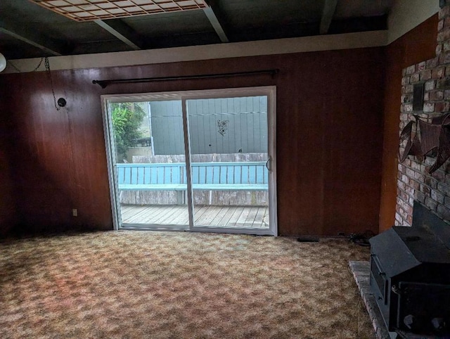 unfurnished living room featuring carpet and a wood stove