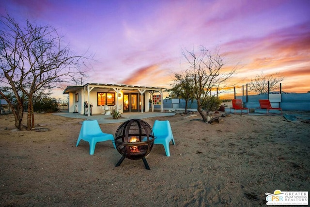 back house at dusk with a patio area and an outdoor fire pit