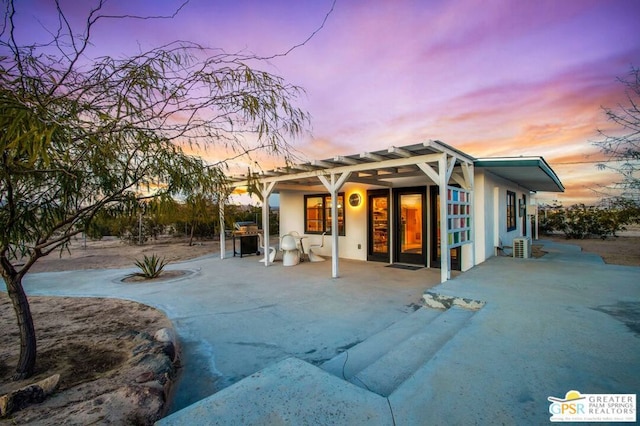 back house at dusk with a patio area and a pergola