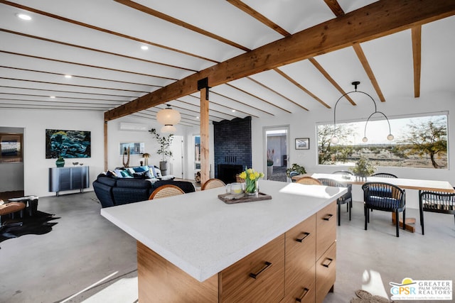 kitchen featuring decorative light fixtures, vaulted ceiling with beams, a fireplace, and a center island