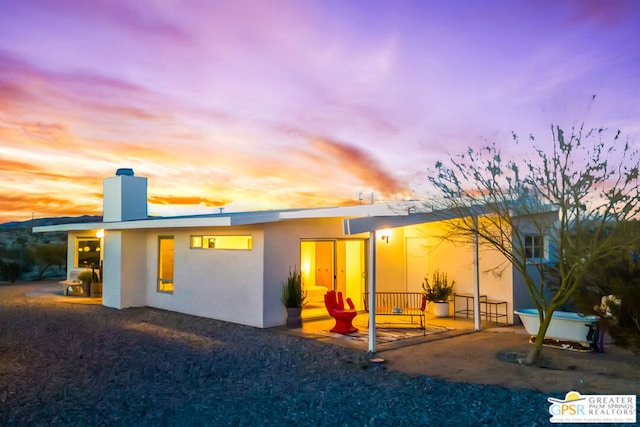 back house at dusk with a patio area