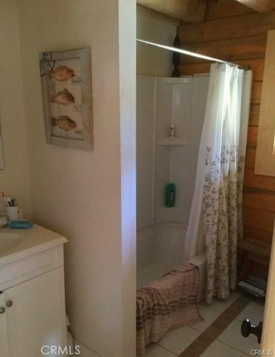 bathroom with vanity, shower / bath combo, tile patterned floors, and wooden walls