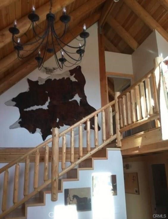 staircase with an inviting chandelier, wood ceiling, and lofted ceiling with beams