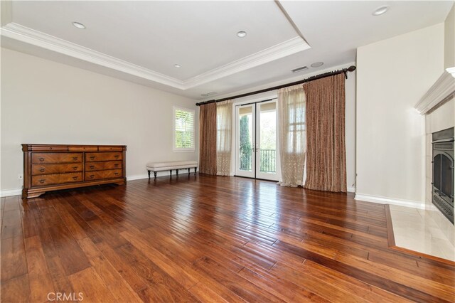 unfurnished living room featuring ornamental molding, a raised ceiling, a fireplace, and dark hardwood / wood-style flooring