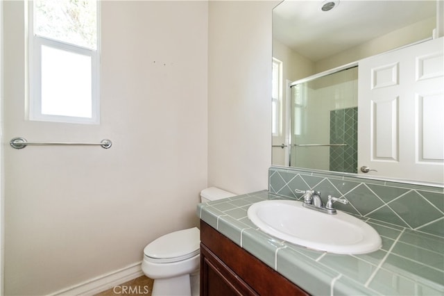 bathroom with decorative backsplash, a shower with shower door, vanity, and toilet