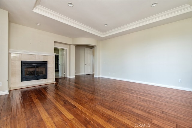 unfurnished living room featuring a tray ceiling, a tile fireplace, hardwood / wood-style flooring, and crown molding