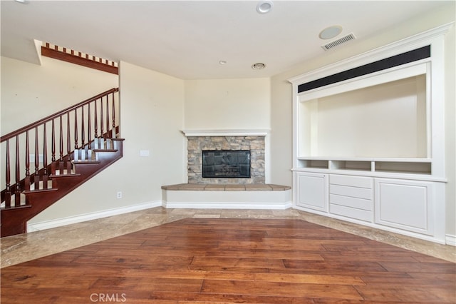 unfurnished living room featuring a stone fireplace and hardwood / wood-style flooring