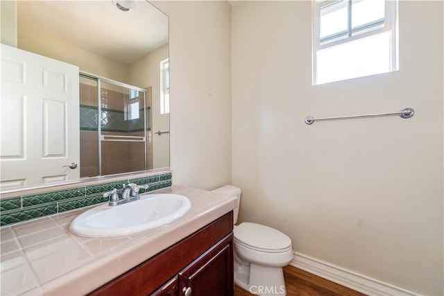 bathroom featuring wood-type flooring, vanity, toilet, and a shower with door