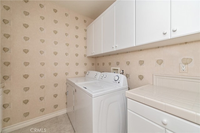 laundry room with cabinets, washing machine and clothes dryer, and light tile patterned flooring