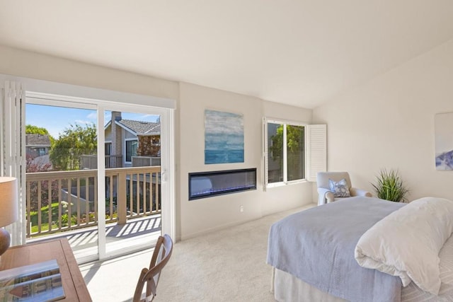 carpeted bedroom with vaulted ceiling and access to outside