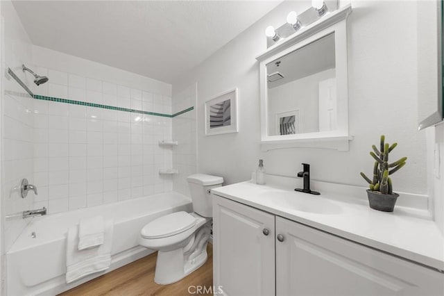 full bathroom with hardwood / wood-style floors, tiled shower / bath combo, toilet, and vanity