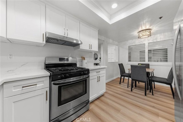 kitchen featuring white cabinetry, light hardwood / wood-style floors, a tray ceiling, appliances with stainless steel finishes, and ornamental molding