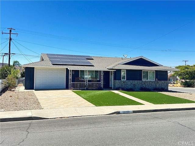 ranch-style home featuring a garage, a front lawn, solar panels, and covered porch