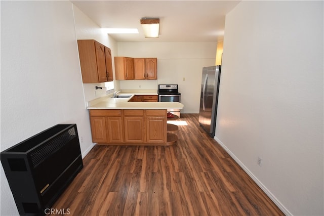 kitchen featuring sink, kitchen peninsula, heating unit, stainless steel appliances, and dark hardwood / wood-style floors