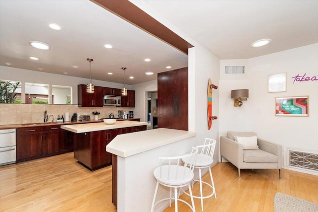 kitchen featuring a kitchen breakfast bar, light hardwood / wood-style flooring, a kitchen island, and hanging light fixtures