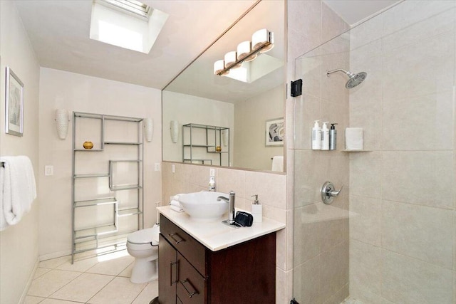 bathroom with vanity, tile patterned floors, a skylight, toilet, and tiled shower