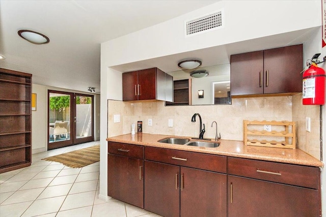 kitchen featuring tasteful backsplash, light tile patterned floors, sink, and french doors