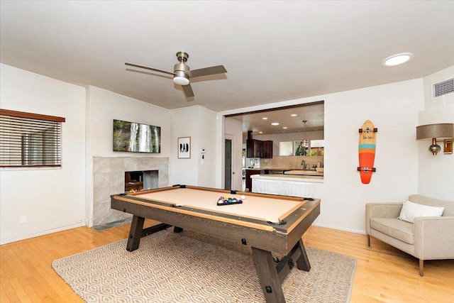 game room with ceiling fan, sink, a high end fireplace, light wood-type flooring, and pool table