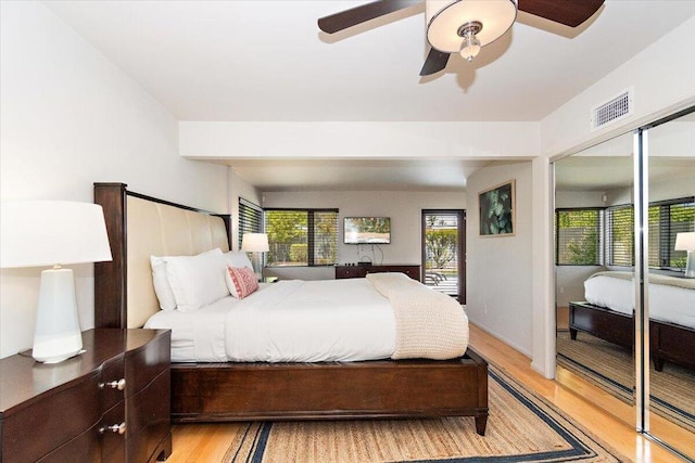 bedroom with a closet, multiple windows, ceiling fan, and light hardwood / wood-style flooring