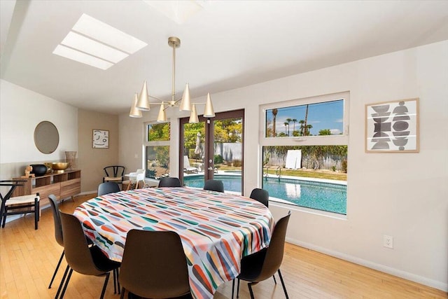 dining area with light wood-type flooring and a skylight