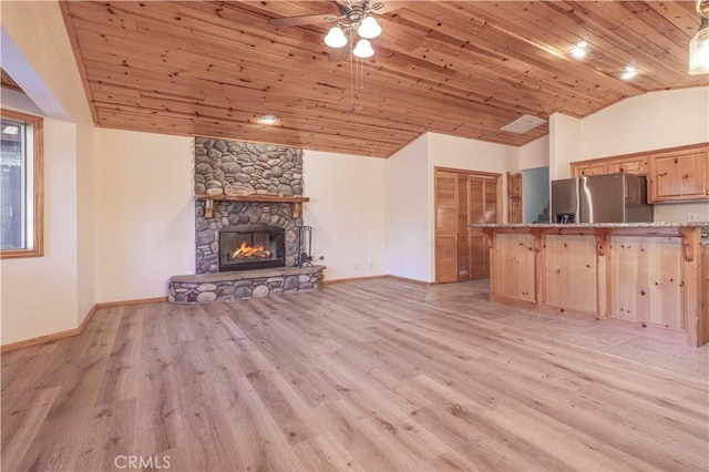 unfurnished living room featuring vaulted ceiling, a stone fireplace, light wood-type flooring, and wooden ceiling