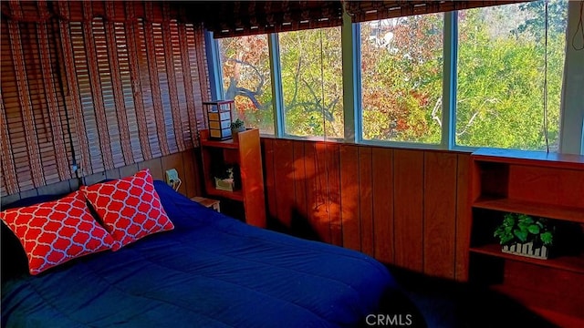 bedroom with wood walls and multiple windows