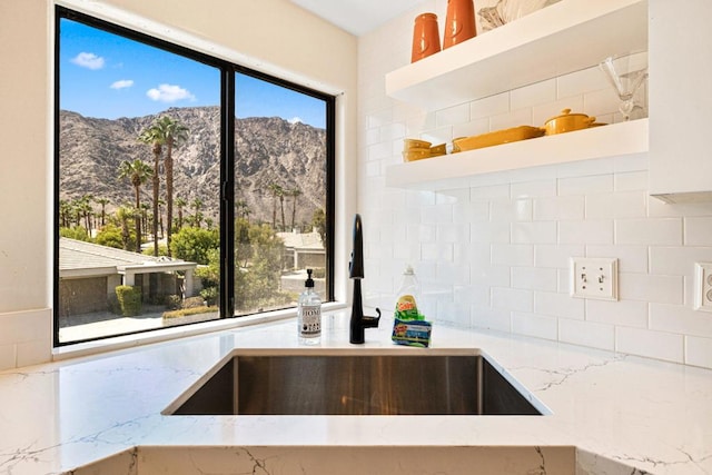 kitchen featuring a wealth of natural light, light stone counters, sink, and a mountain view