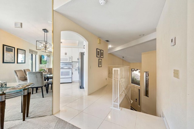 corridor featuring lofted ceiling and light tile patterned flooring