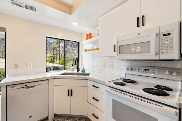 kitchen with backsplash, sink, white appliances, and white cabinets