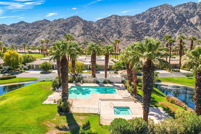 view of pool with a patio area, a water and mountain view, and a yard