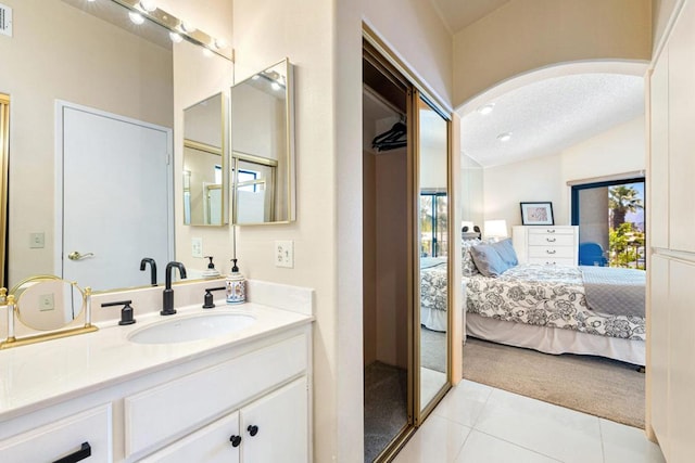 bathroom featuring a textured ceiling, tile patterned flooring, vanity, walk in shower, and vaulted ceiling