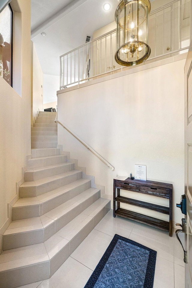 staircase featuring tile patterned floors, a notable chandelier, and beamed ceiling