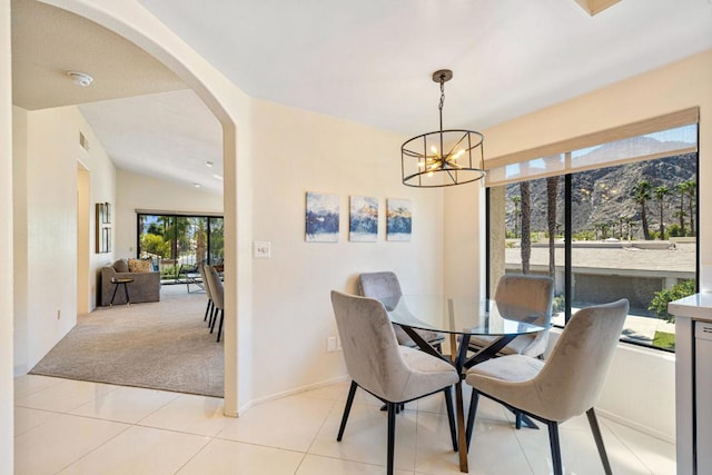 dining space featuring lofted ceiling, light tile patterned floors, and an inviting chandelier