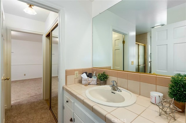 bathroom featuring vanity, decorative backsplash, and a shower with door