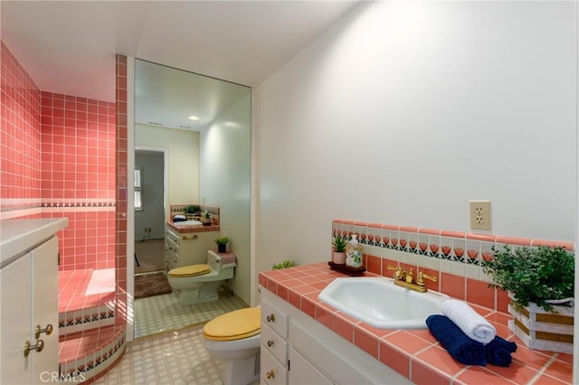 bathroom with vanity, toilet, and tile walls